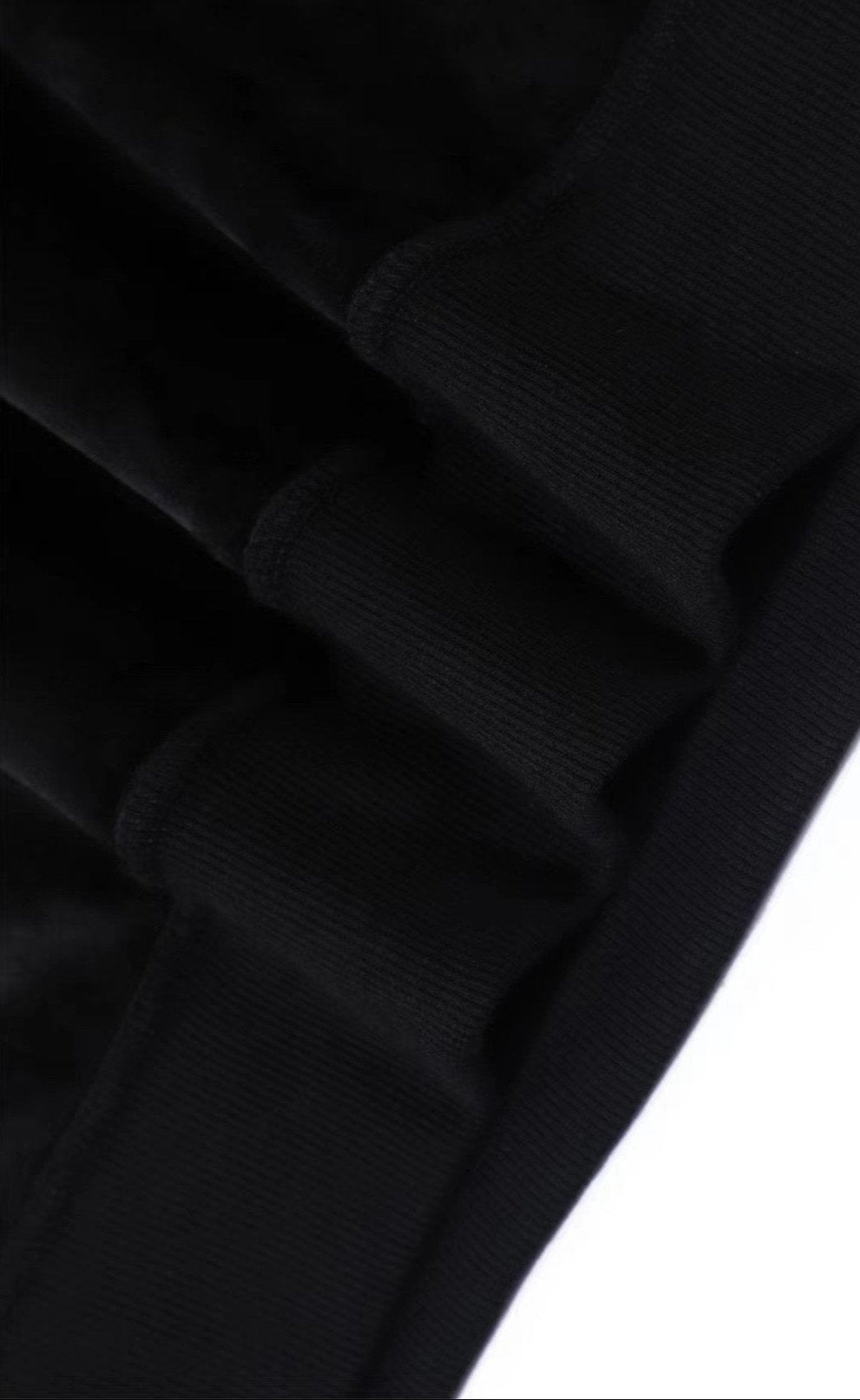 Detail of elasticized hem and cuffs on a black cashmere hoodie, showcasing its soft texture and refined quality.